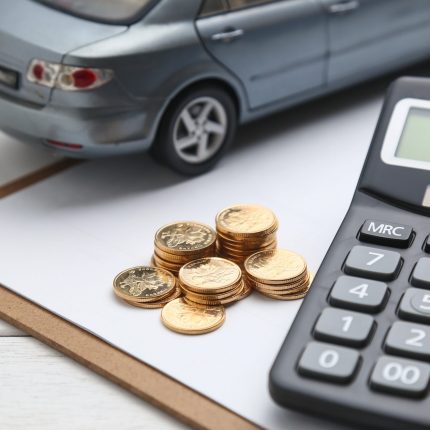 car model,calculator and coins on white table